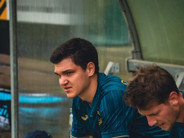 Dva hráči Diversa na střídačce sledují hru