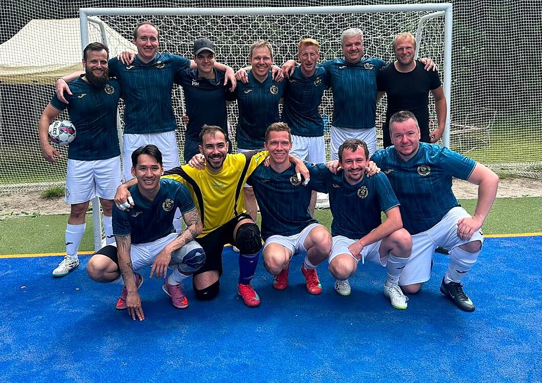 Dvanáct hráčů Diversa CF u branky na modrém hřišti, přední řada v podřepu